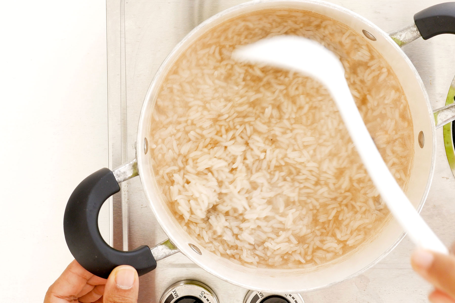 Placing long-grain rice in a pot.