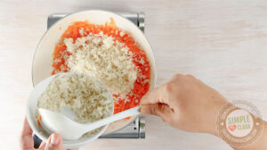 Adding rice to skillet with carrot