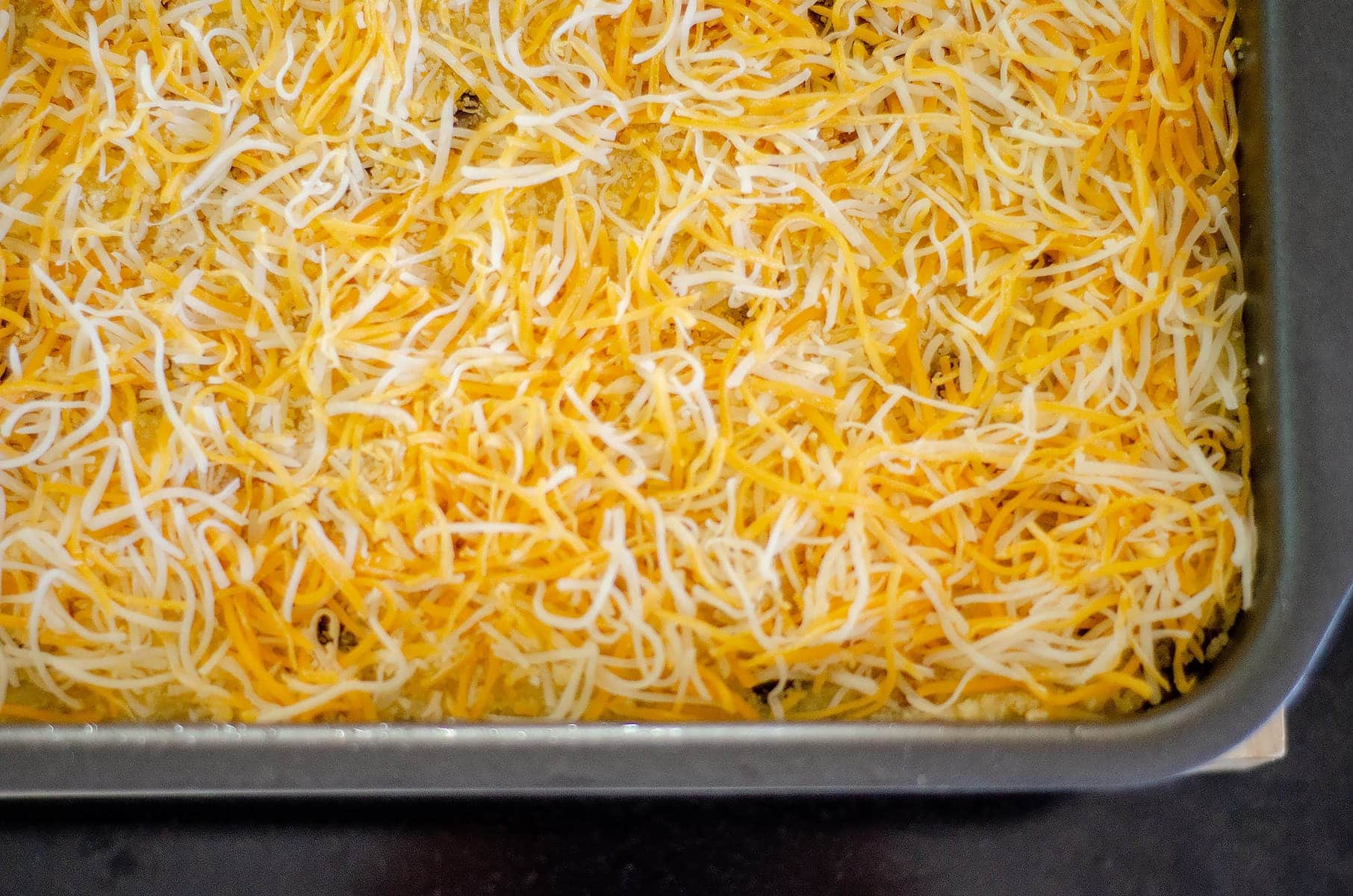 Layered cornmeal casserole topped with cheese