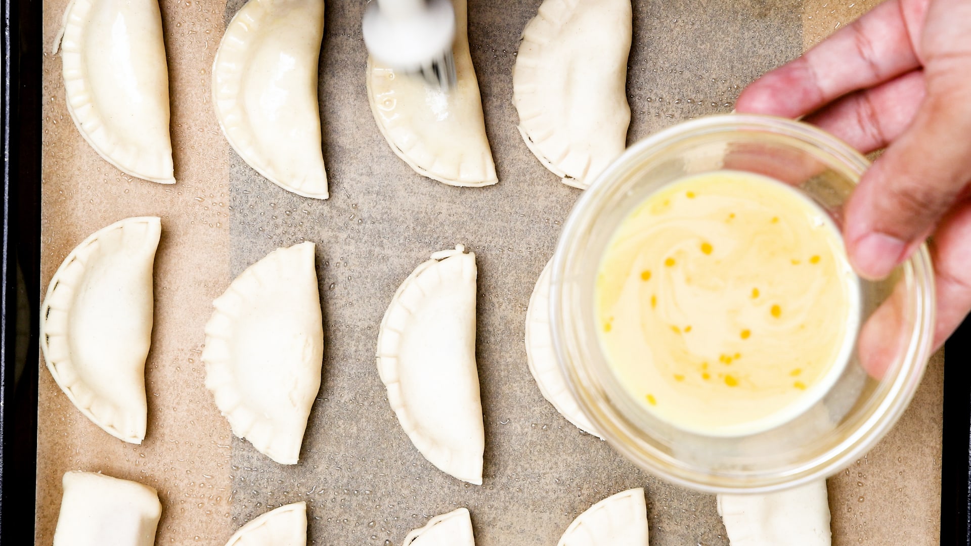 Brushing empanadas with eggwash.