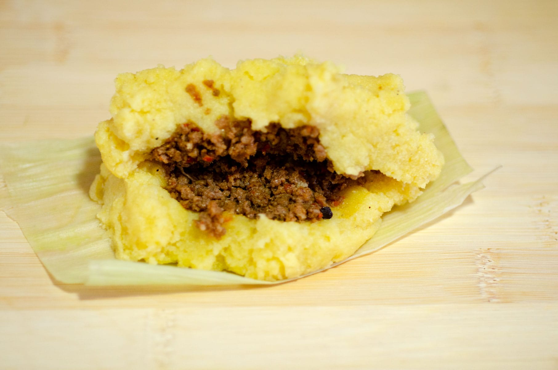 Meat between two layers of cornmeal paste, on a corn husk leaf