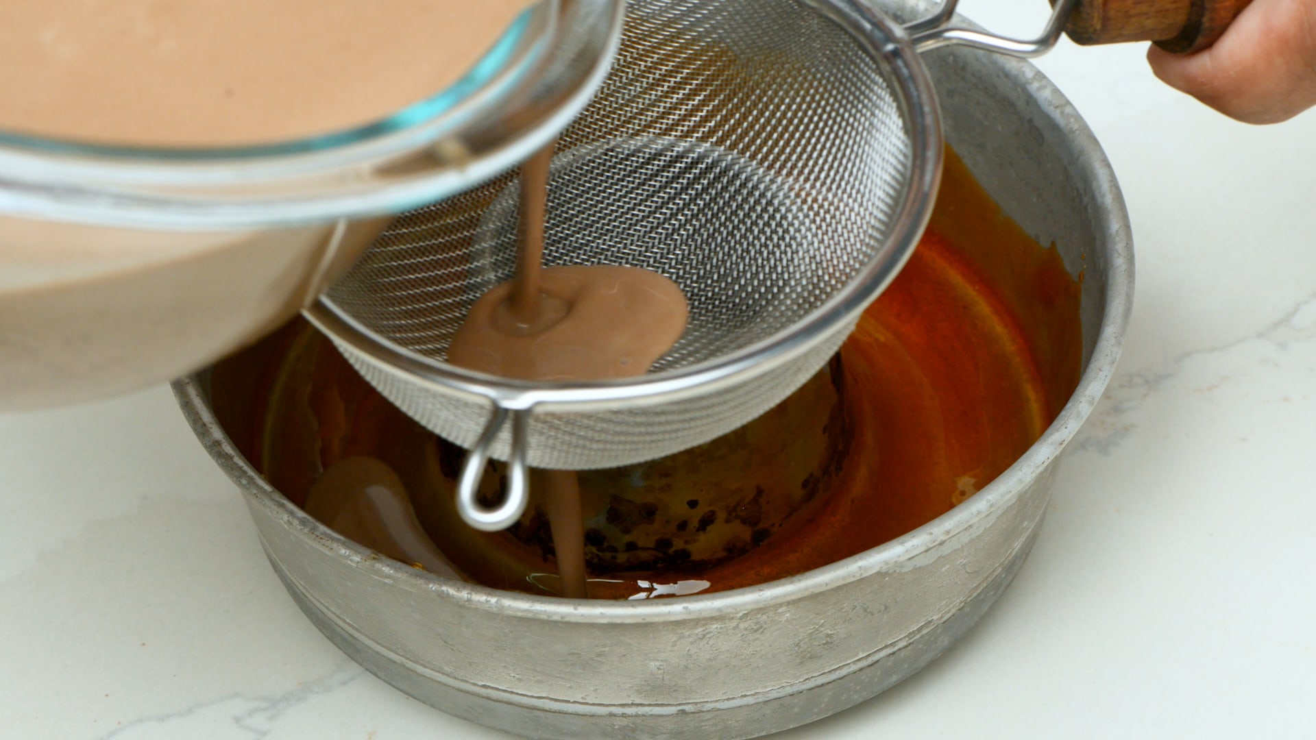 Pouring flan mixture into mold.