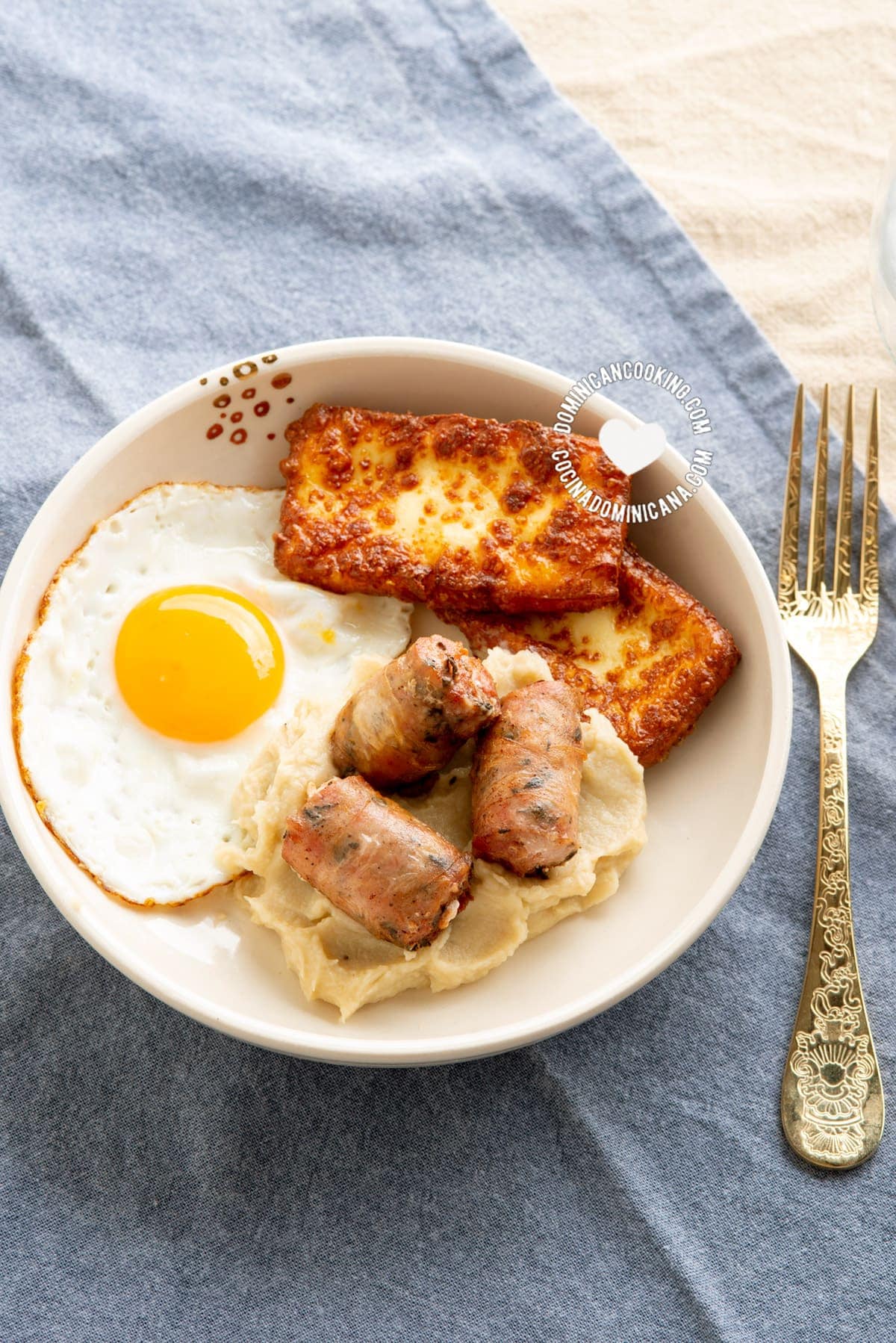 Dominican keto breakfast of fried cheese, egg and sausage with mash seen from above