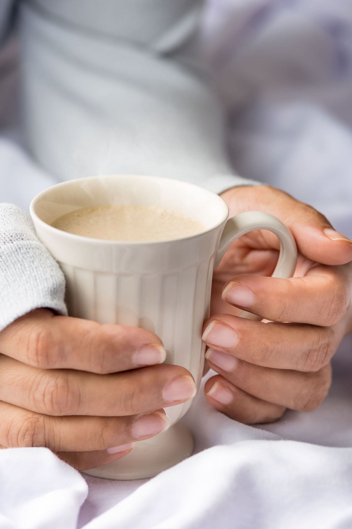 Hands holding a cup of ponche de desayuno (breakfast eggnog).