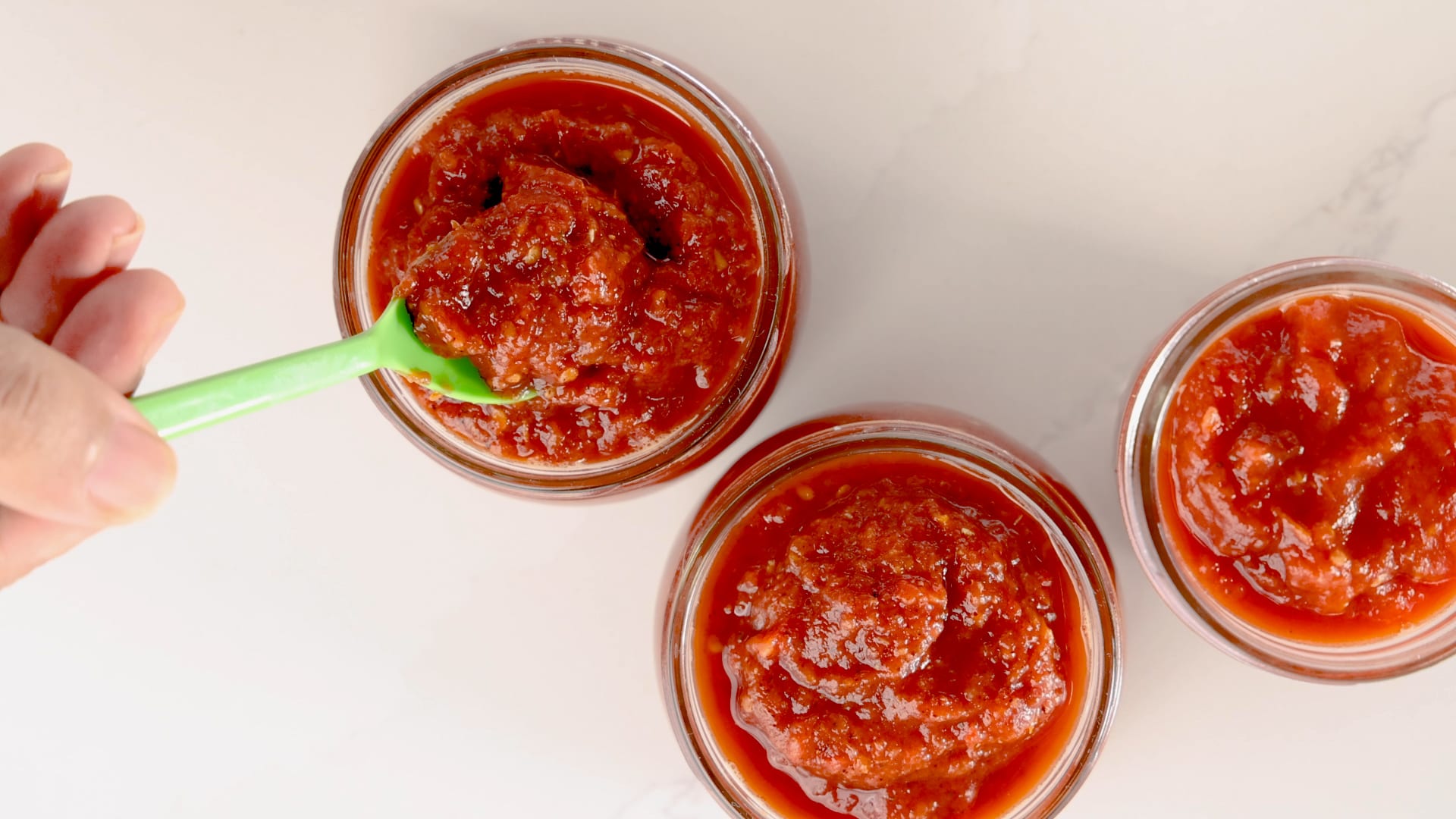 Scooping tomato sauce into jars